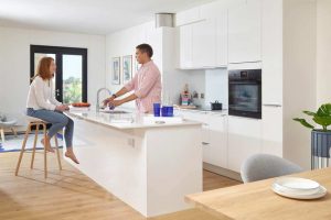 A man and a woman in a modern kitchen with an island unit