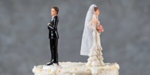 Bride and groom cake toppers facing away from each other on cake