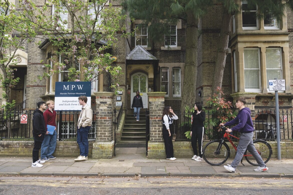 The outside of a building on a street with students standing outside