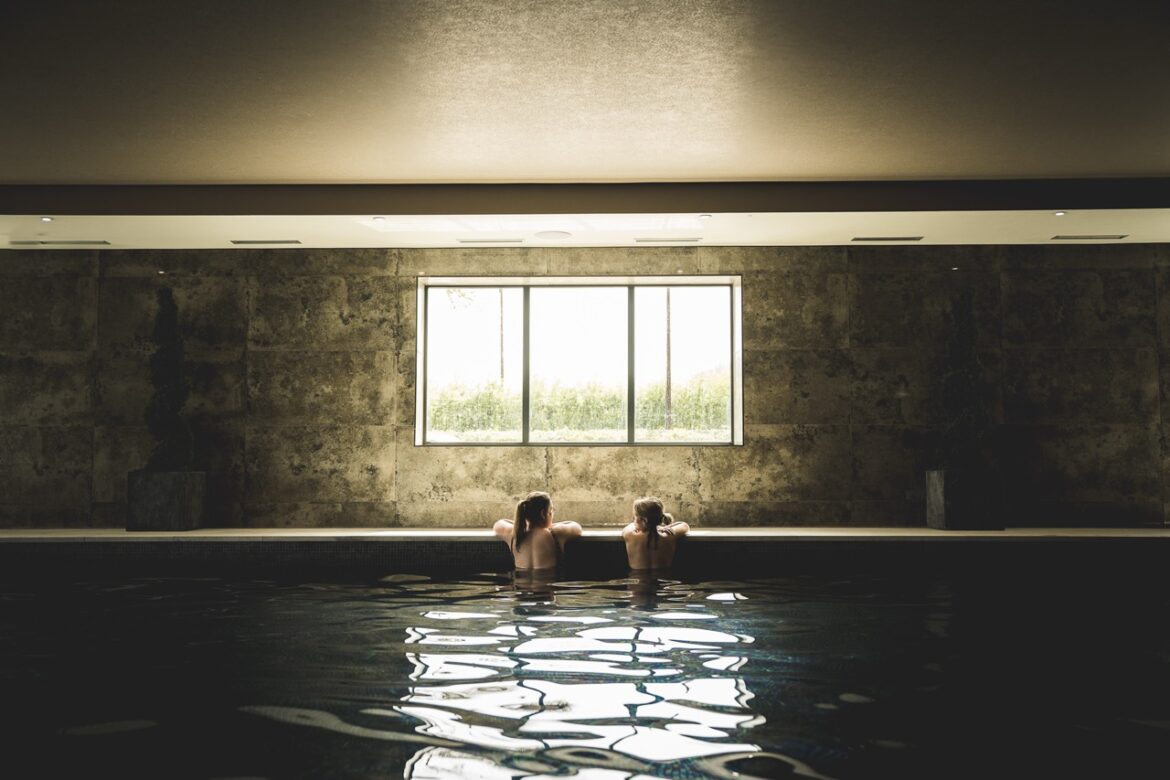 Two people sitting in a swimming pool near a window