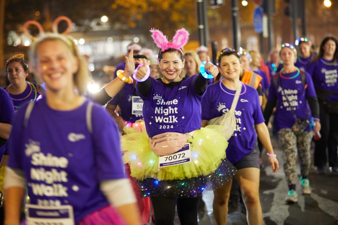 A group of people wearing purple t-shirts and costumes outside at night