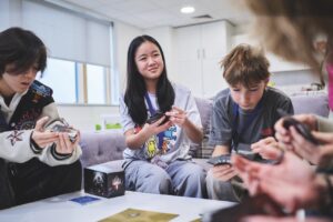 A group of teenagers sit round a table playing a card game