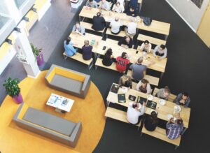 Top view of a modern office space with multiple wooden tables and benches