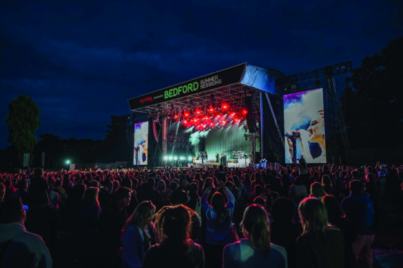 An outdoor stage at night. A large crowd stands in front