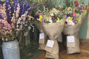 Flower bouquets in brown paper and metal buckets resting against a wall