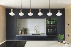 Over the top of a counter in a modern kitchen with hanging lightbulbs and sleek black and white surfaces