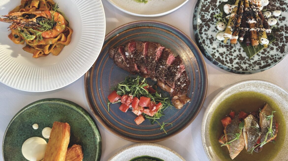 A top view of a table filled with different dishes, including a steak, soup and prawns