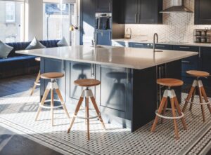 A modern kitchen space with a large island and stools and exposed ceiling