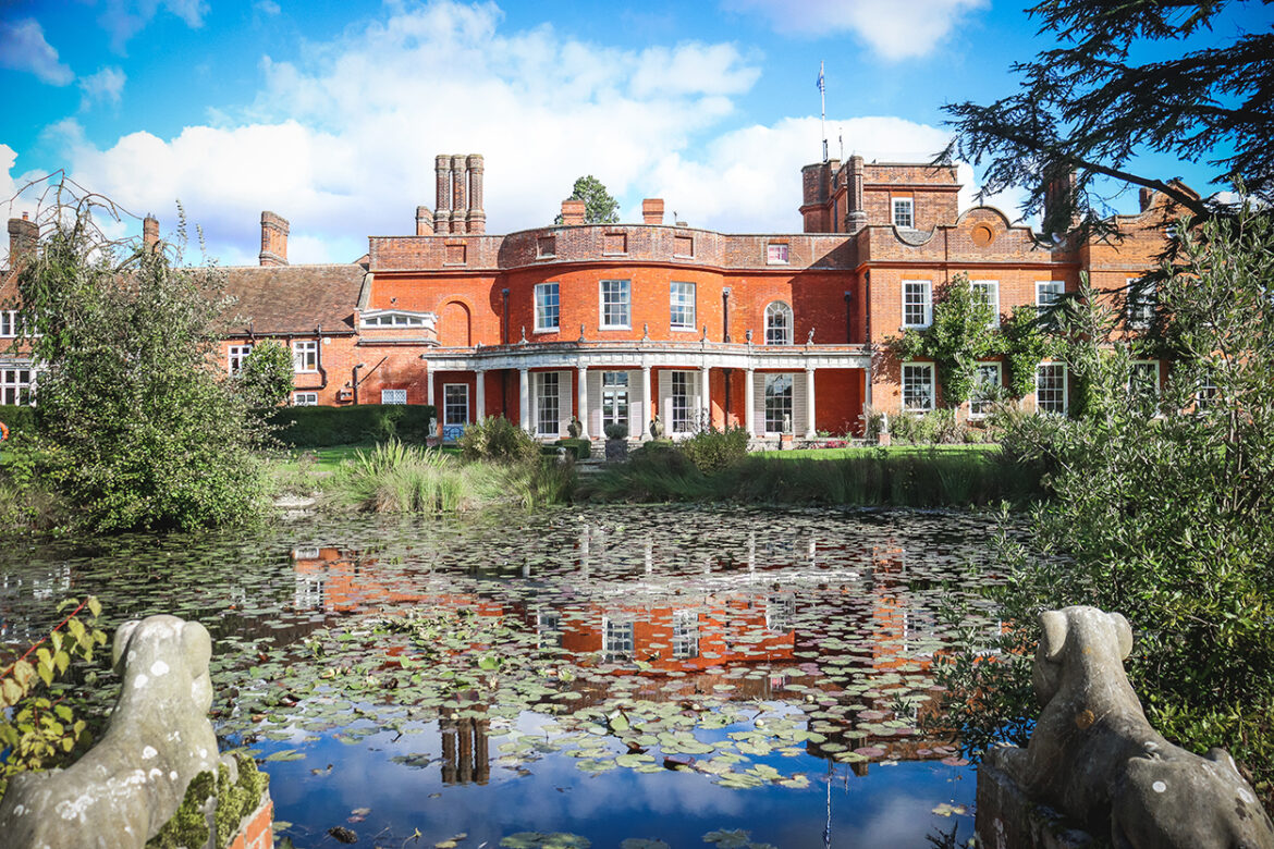 An old building with a pond and trees in front
