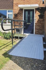 A metal ramp with a handle bar placed leading to the front door of a house
