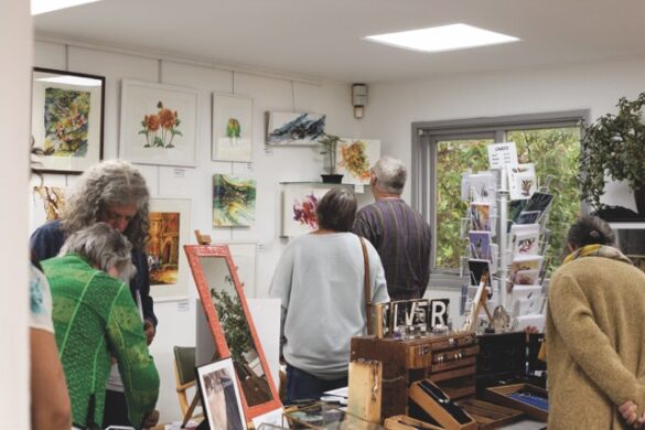 A group of people looking at paintings on a wall in a light and airy gallery