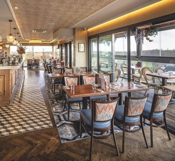 A light restaurant with large windows, a bar area, and tables and chairs