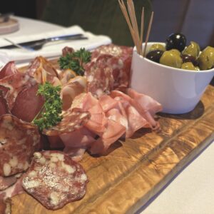 A selection of meats and olives on a charcuterie board