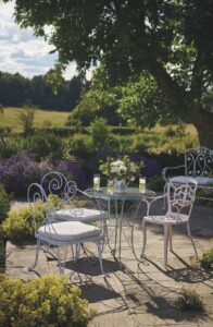 Metal chairs and table placed outside, surrounded by long grass and trees