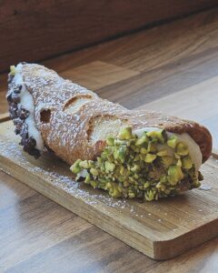 A cannoli eith ricotta, dipped chocolate chips and chopped pistachios