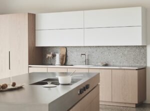 A modern kitchen with white and wood cabinets and a metal island area