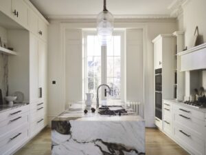 A modern kitchen with long white cabinets and a modern white and brown island area