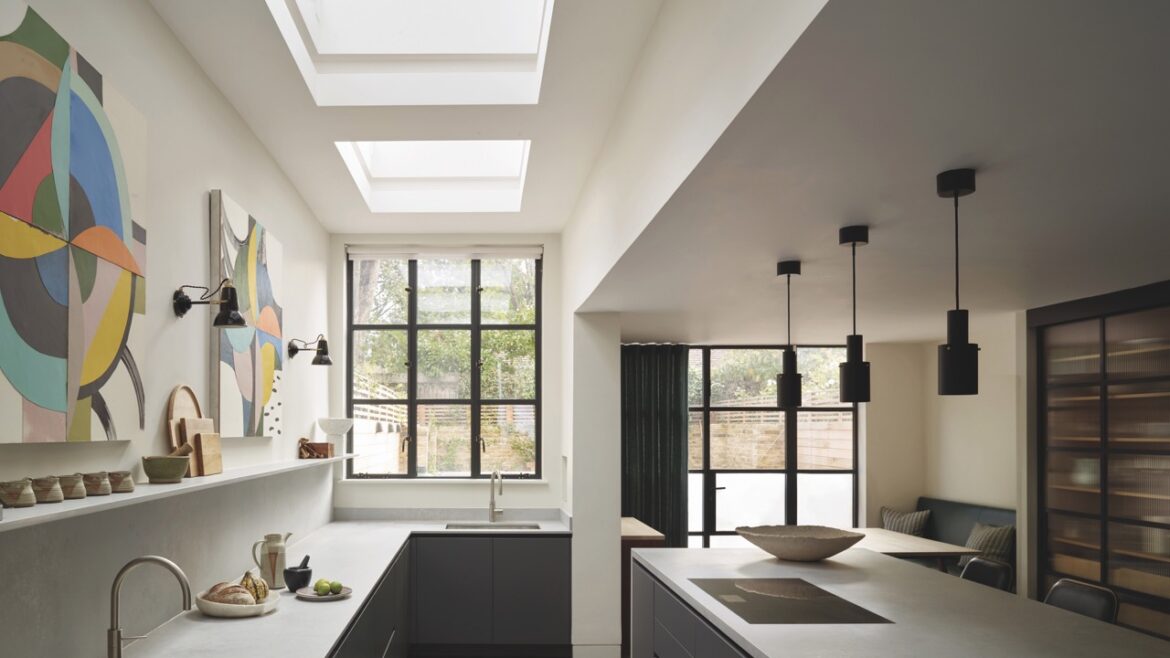 A modern kitchen with a sleek island and large windows. There is modern artwork on the walls above the tap