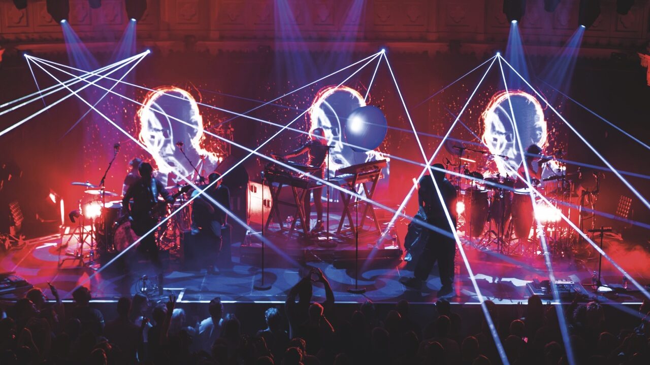 A band onstage in red and white strobe lighting