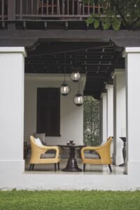 An outdoor seating area with yellow chairs in-between white pillars