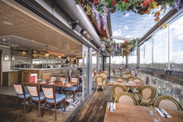 The interior of a restaurant with a bar, table inside and seating in a conservatory area with flowers on the ceiling
