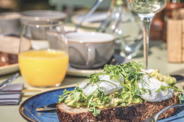A plate of egg on toast with a glass of wine and orange juice on the table next to it