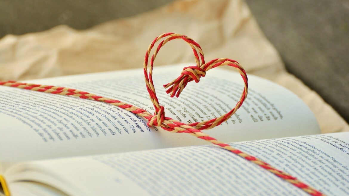An open book with red string making a heart shape spread over the pages