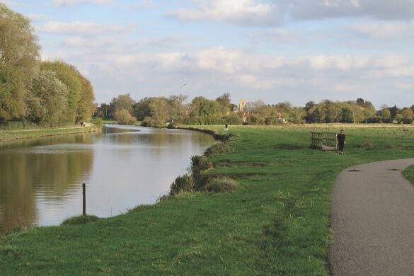A river next to a bank and concrete path winding round a bend
