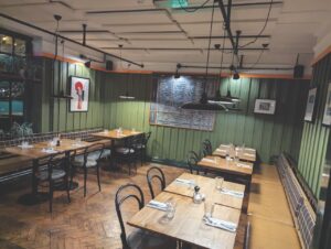 The inside of an empty restaurant with rows of tables and green walls