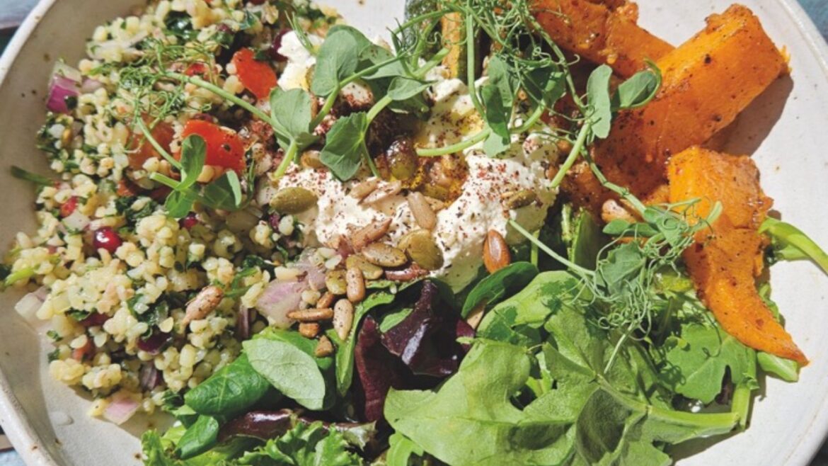 A top-view of a colourful salsa with leaves, nuts and potato