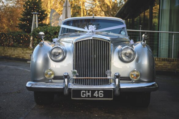 162-Libby & Barney SMALL Large A silver car with ribbons attached to the front for a wedding standing outside The Gonville Hotel