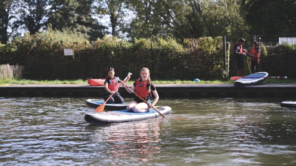Students at the Stephen Perse Cambridge school experience paddle boarding on a lake