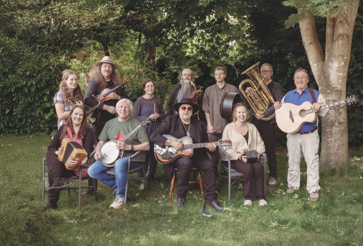 A folk band taking a group photo holding their instruments in a field