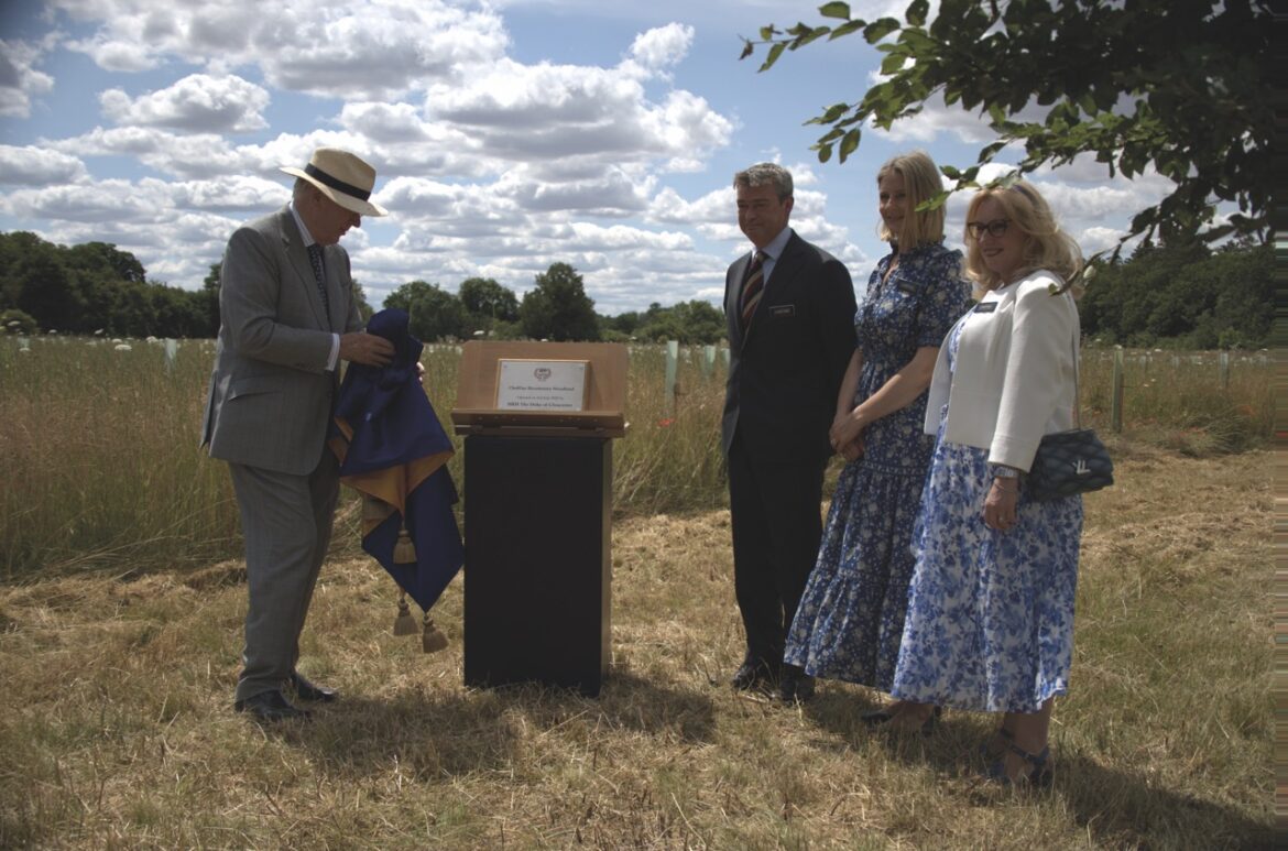 A group stands in a field in Fulbourn next to a wooden plinth as an opening ceremony