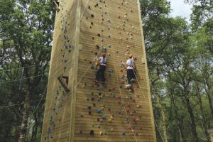 A tall climbing tower with students from Gresham's scaling the side