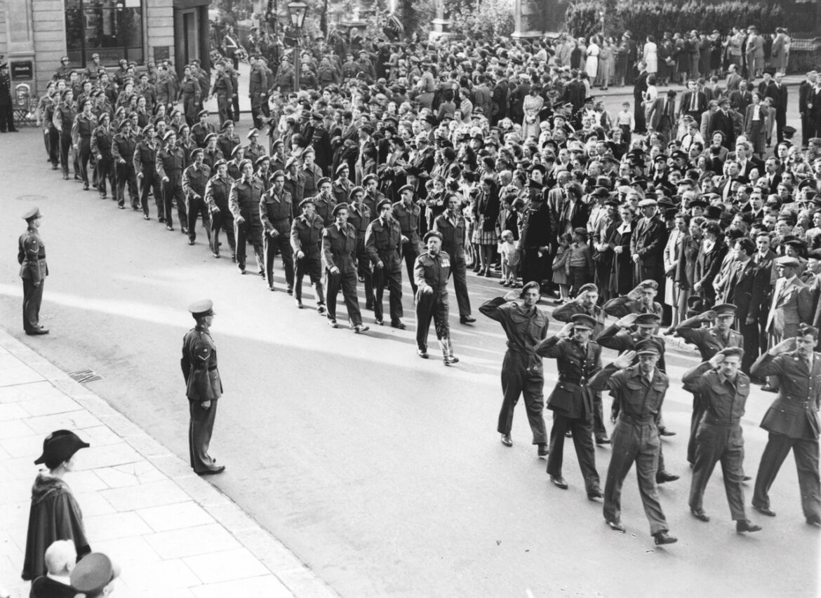 A black and white photo of soldiers marching down the street