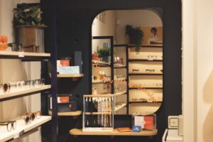 Corner of a store with shelves filled with glasses and jewellery, and a mirror hung on the wall