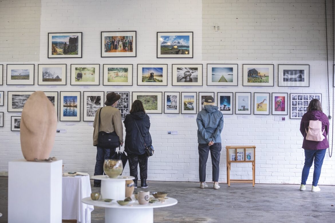 An art exhibition showing photos on the walls and sculptures in the centre of the room