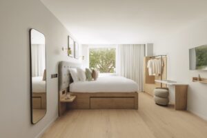 A clean and modern bedroom with a large double bed and mirror on the wall