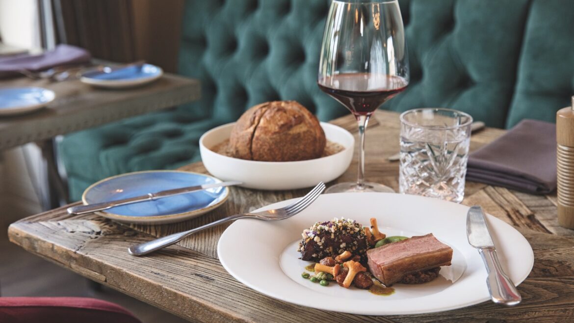 Numerous plates on a wooden table with a glass of wine behind