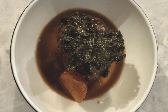 Top view of a brown meat and vegetable dish in a white bowl