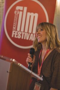 A woman standing at a podium with a microphone at the Cambridge Film Festival