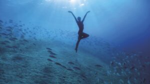 A diver striking a pose in the blue ocean underwater