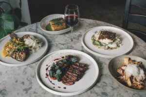 A table of gourmet foods and a glass of red wine in the middle