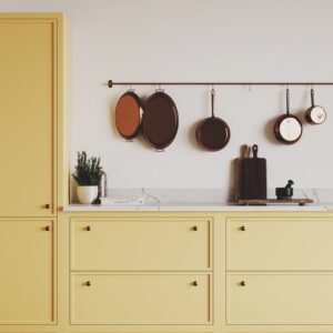 A kitchen with yellow cupboards and pans hanging from the wall
