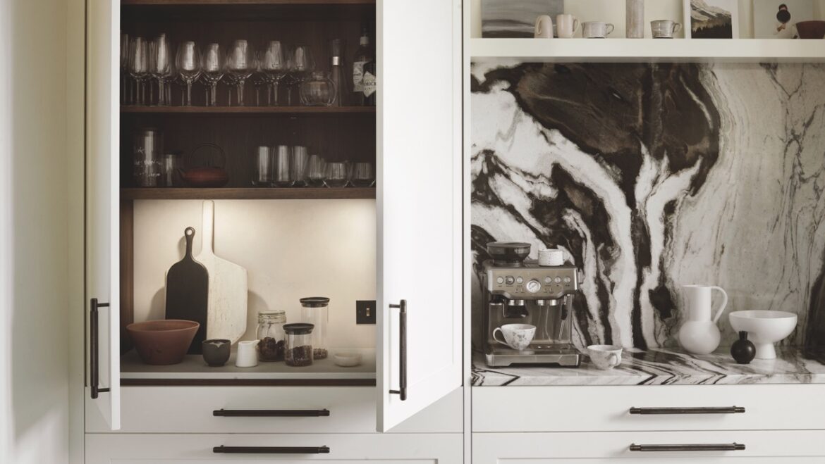 The open cupboards and counter of a modern kitchen with black and white marble