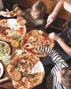 Top view off children tucking into large pizzas on a table