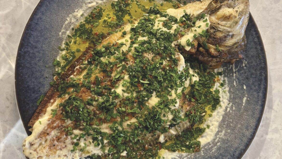 Top view of a fish dish covered with green seasoning