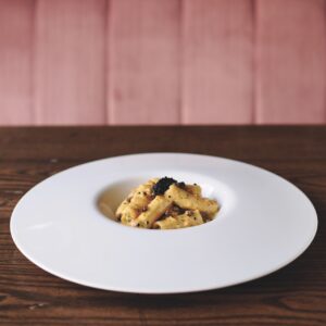 A white plate with a large rim and pasta in the middle