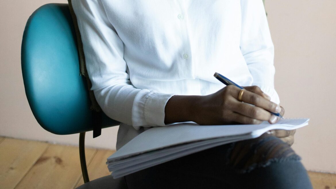 A woman sitting on a chair and writing in a notebook